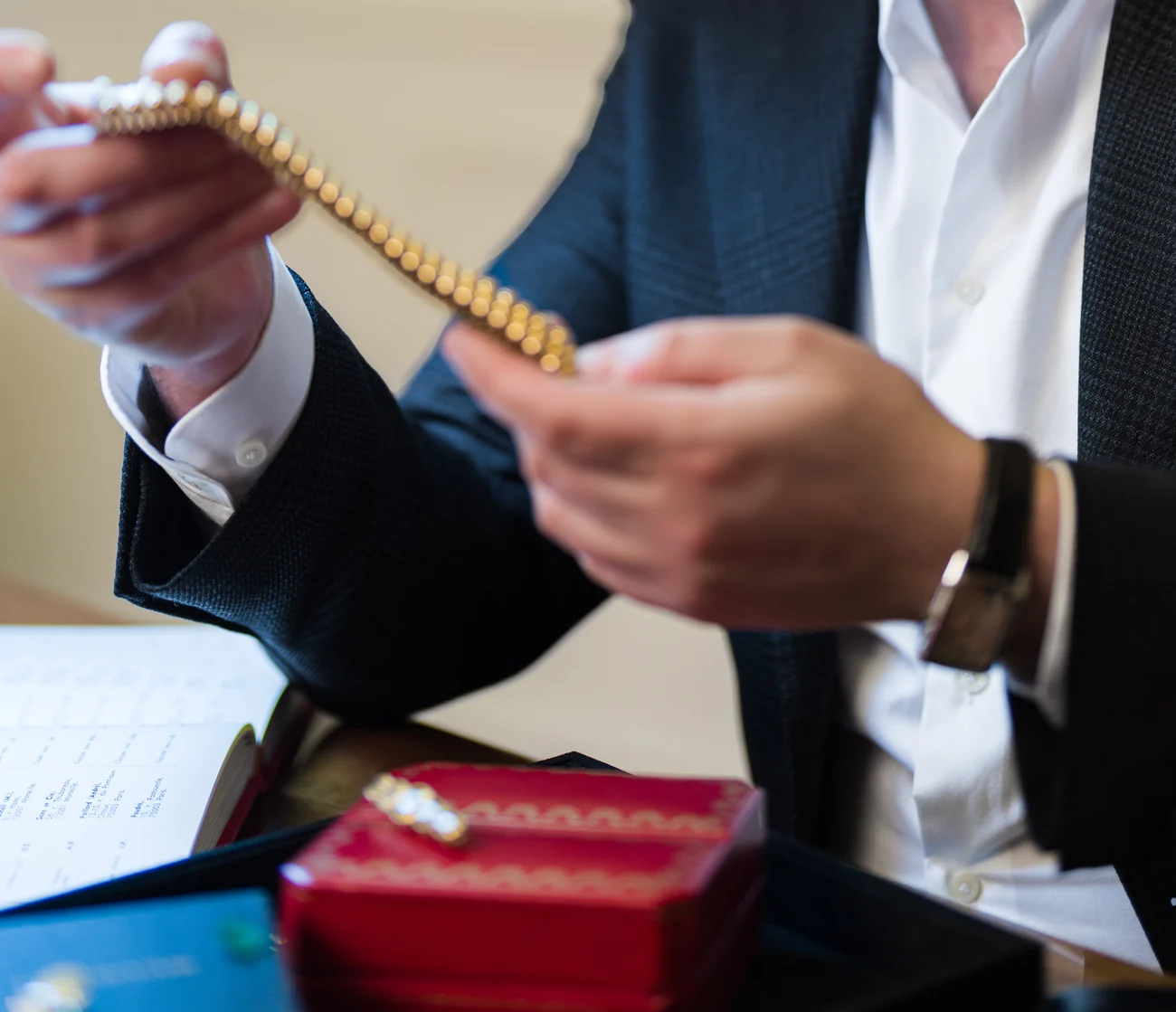 Un bracelet en or examiné à deux mains, au-dessus des écrins